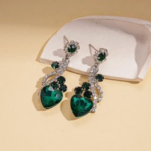 Detail of luxury silver earrings with heart-shaped green gems and sparkling rhinestones