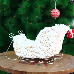 White plush Christmas sleigh decor with golden leaf patterns on wooden table