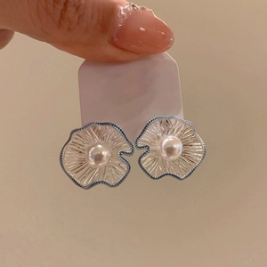 Detail of flower pearl stud earring with silver frame and unique blue dot edging detail