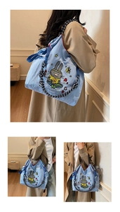 Close-up of light blue canvas tote bag with cartoon design and thick woven rope straps