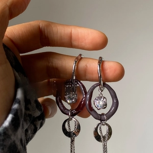 Detailed macro view of long silver tassel earrings with purple resin rings and zircon