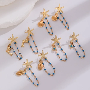 Golden ocean earrings set with starfish and blue beaded tassels on white stone
