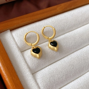Retro matte gold heart drop earrings with black faceted gemstones on white velvet display