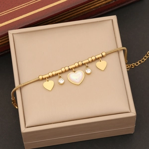 Golden stainless steel heart pendant necklace with pearls and charms on a jewelry box
