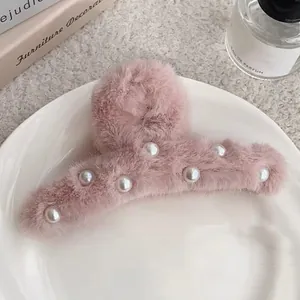 Détail de la pince à cheveux en peluche rose avec d'élégantes perles blanches