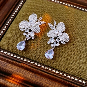 Nahaufnahme von Silber-Zirkonia-Ohrringen in Blumenform auf einem dunkelgrünen Samtkissen
