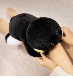 Gros plan d'une peluche pingouin douce tenue en mains pour montrer sa texture