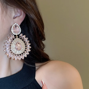 Detail of pink pear-cut rhinestone drop earrings with sparkling floral halo on model