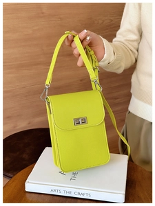 Detailed shot of vibrant neon green textured leather mini phone bag with silver metal clasp