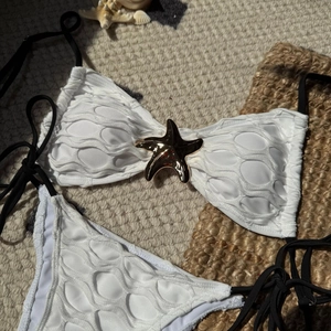 Detail of white bubble texture bikini top featuring a golden starfish and black ties