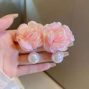 Close-up of pink fabric flower earrings with white pearls and elegant luster finish