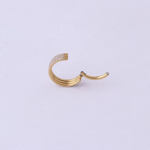 Detail of golden hinged ring with triple rows of zircon stones for nose or ear piercing