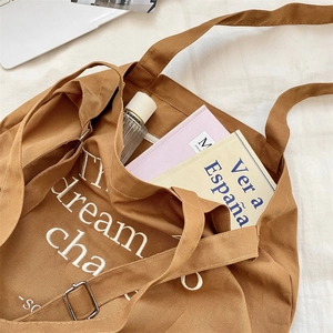 Close-up of brown canvas tote bag featuring white embroidery and adjustable strap detail