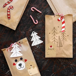 Brown kraft paper Christmas gift bags with tags, candy canes, and festive red twine cords