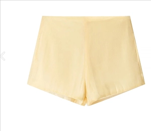 Detailed view of pale yellow satin shorts featuring smooth silk texture and high waist cut