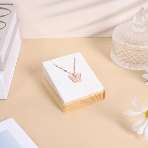 Detail of a butterfly pendant with pink stone on a white velvet jewelry display stand
