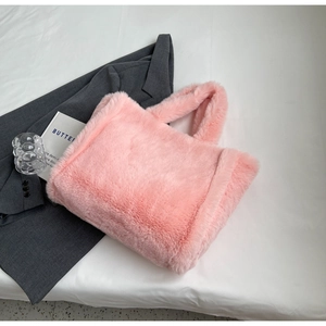 Detail view of pink faux fur tote bag with plush texture on minimalist white bedding