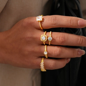 Detailed view of five-piece gold ring set featuring square and round zircon stones on hand