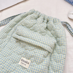 Detail of blue and yellow plaid quilted backpack featuring heart stitching and woven label