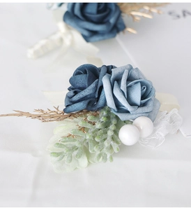 Close-up of blue artificial rose corsage with gold branches, lace and white pearls