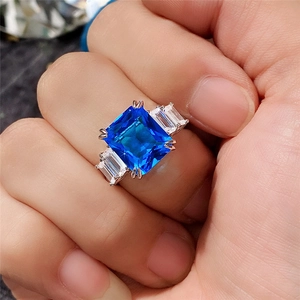 Macro shot of a 10x12 square blue zircon ring with side baguette diamonds on hand