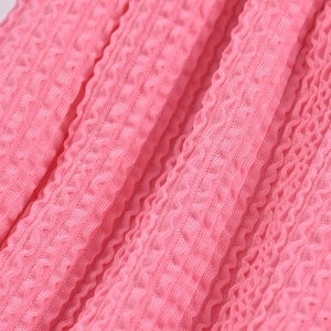 Détail de la texture du tissu seersucker rose avec une structure 3D plissée unique