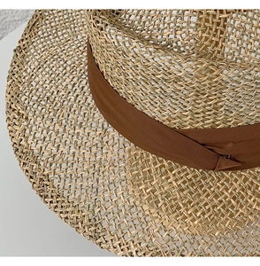Detailed close-up showing the natural seagrass texture and brown ribbon on the sun hat