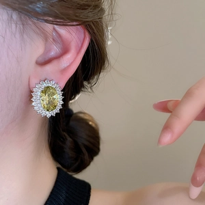 Close-up of model wearing oval yellow zircon stud earrings with silver setting