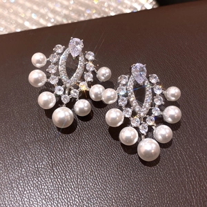 Primo piano di orecchini vintage in argento con strass e perle eleganti.