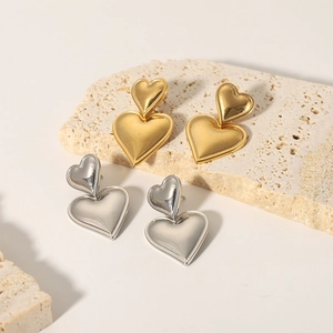 Orecchini a cuore minimalisti in oro 18K e argento su un supporto in pietra