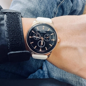 Detail of rose gold case sports watch with white silicone strap and rhinestone markers