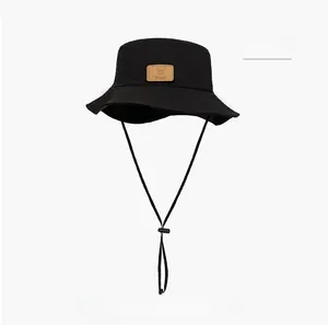 Detail of black breathable sun hat with brown leather logo patch and adjustable chin strap