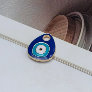 Macro shot of blue teardrop-shaped Evil Eye pendant with polished gold metal edging