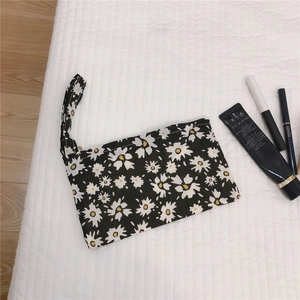 Détail de la petite pochette en tissu noir à motif marguerites avec fermeture éclair