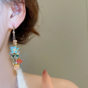 Close-up of floral tassel earrings with blue flowers and red petals on a model