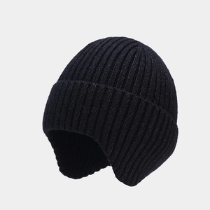 Detail of black ribbed knit beanie featuring warm ear flaps and thick wool texture