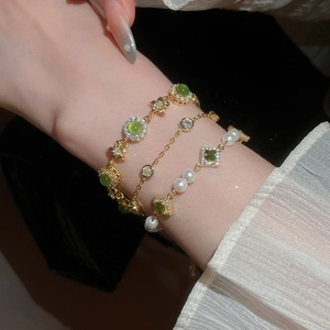 Detailed macro of gold-plated layering bracelets with green zircon, opal and pearls
