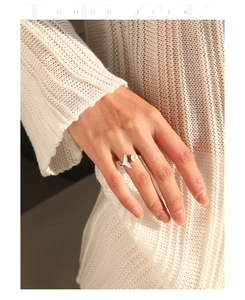 Detailed shot of an S925 silver mermaid tail ring with a pearl on a knit sleeve