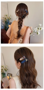 Dettaglio dei fermagli per capelli a fiori blu e marmorizzati indossati su capelli intrecciati