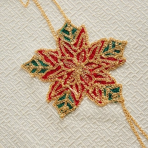 Handcrafted gold wire star ornament with festive red and green embroidery on linen background