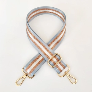 Detail of adjustable nylon bag strap with light blue, white, and gold glitter stripes