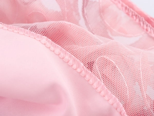 Detalle macro de encaje floral rosa y textura de costura en un vestido de volantes