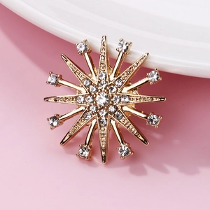 Detailed macro view of a golden starburst brooch featuring shimmering clear crystals