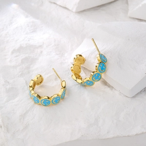 Gold-plated C-shaped earrings with blue enamel smiley face design on stone base