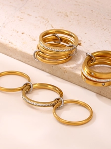 Detail of multi-layer gold plated rings with zircon inlay on a textured stone surface
