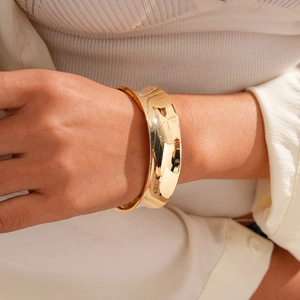 Close-up of wide polished gold geometric open cuff bracelet on a female wrist