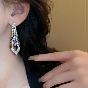 Close-up of elegant tassel earrings with sparkling rhinestones and a purple gemstone drop