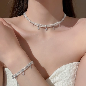 Detailed view of double-layer pearl necklace and bracelet set with teardrop zircon charms
