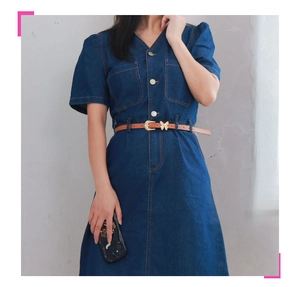 Detail of a brown leather skinny belt with a gold butterfly buckle on a denim dress