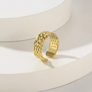 Anello aperto intrecciato placcato oro 18K su sfondo geometrico bianco minimalista